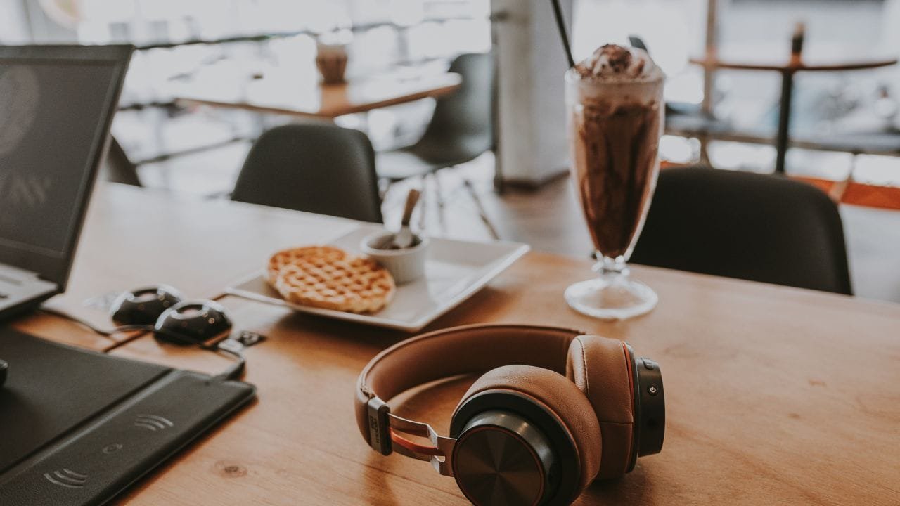 A laptop and headphones on a wooden table.